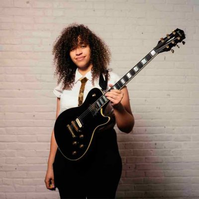 Jackie Venson tocando la guitarra eléctrica sobre un escenario
